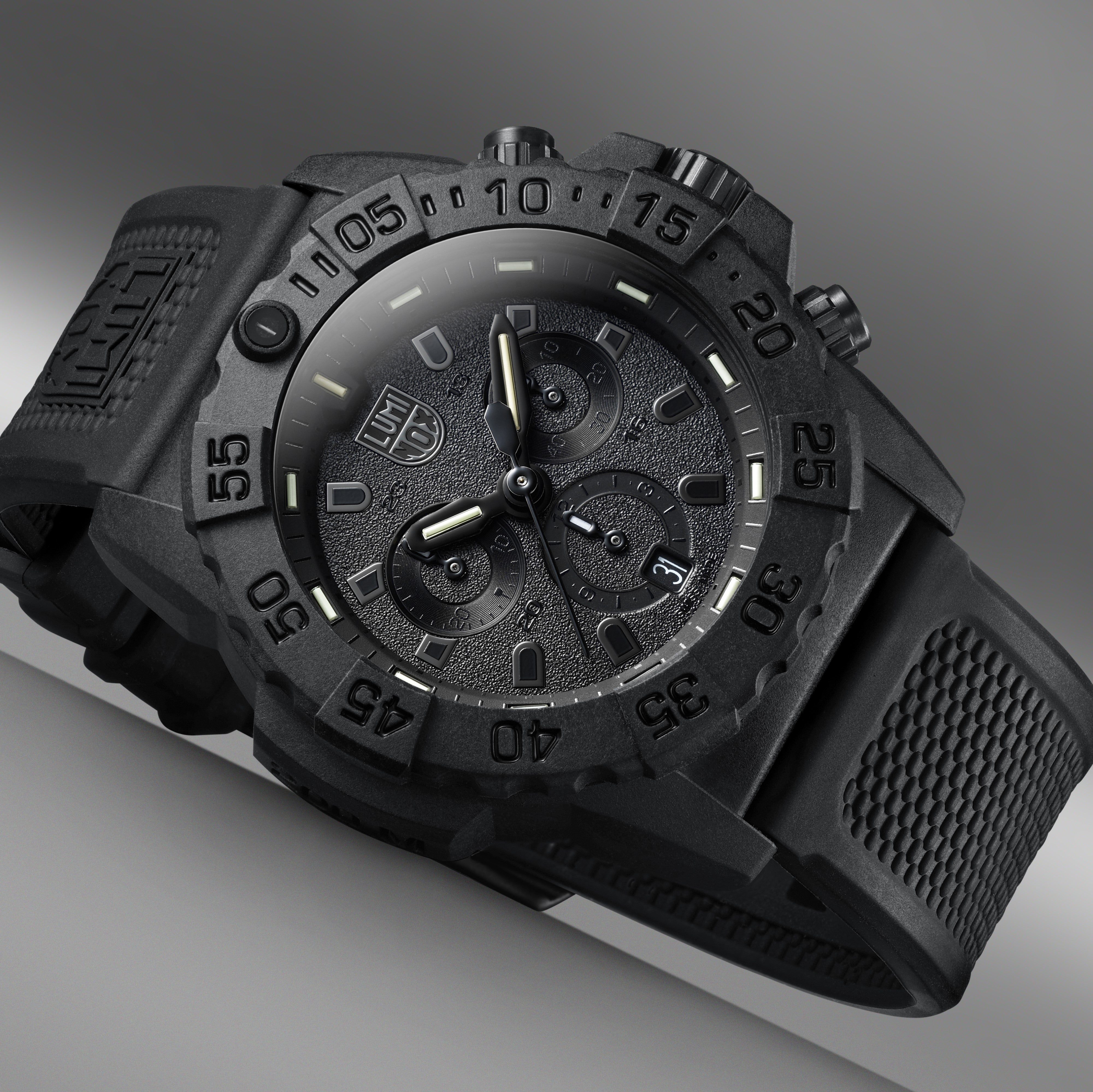 Close-up perspective of the Luminox Canada Navy SEAL Chronograph 3581.BO Swiss Watch highlighting the texture and design. 44 mm Carbon Compound case and case back Carbon Compound unidirectional ratcheting bezel Tempered scratch resistant mineral crystal Swiss quartz movement Water resistant to 200 meters Signature black NBR strap with stainless steel signature buckle Luminox self-powered illumination Swiss Made Replacement Strap FPX.2401.20B.1.K Manual GGM.L002.GMT GGM.L014 2 Year Limited Warranty 10 Year